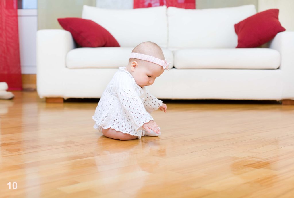 Happy baby girl tuching a hardwood floor flooring services